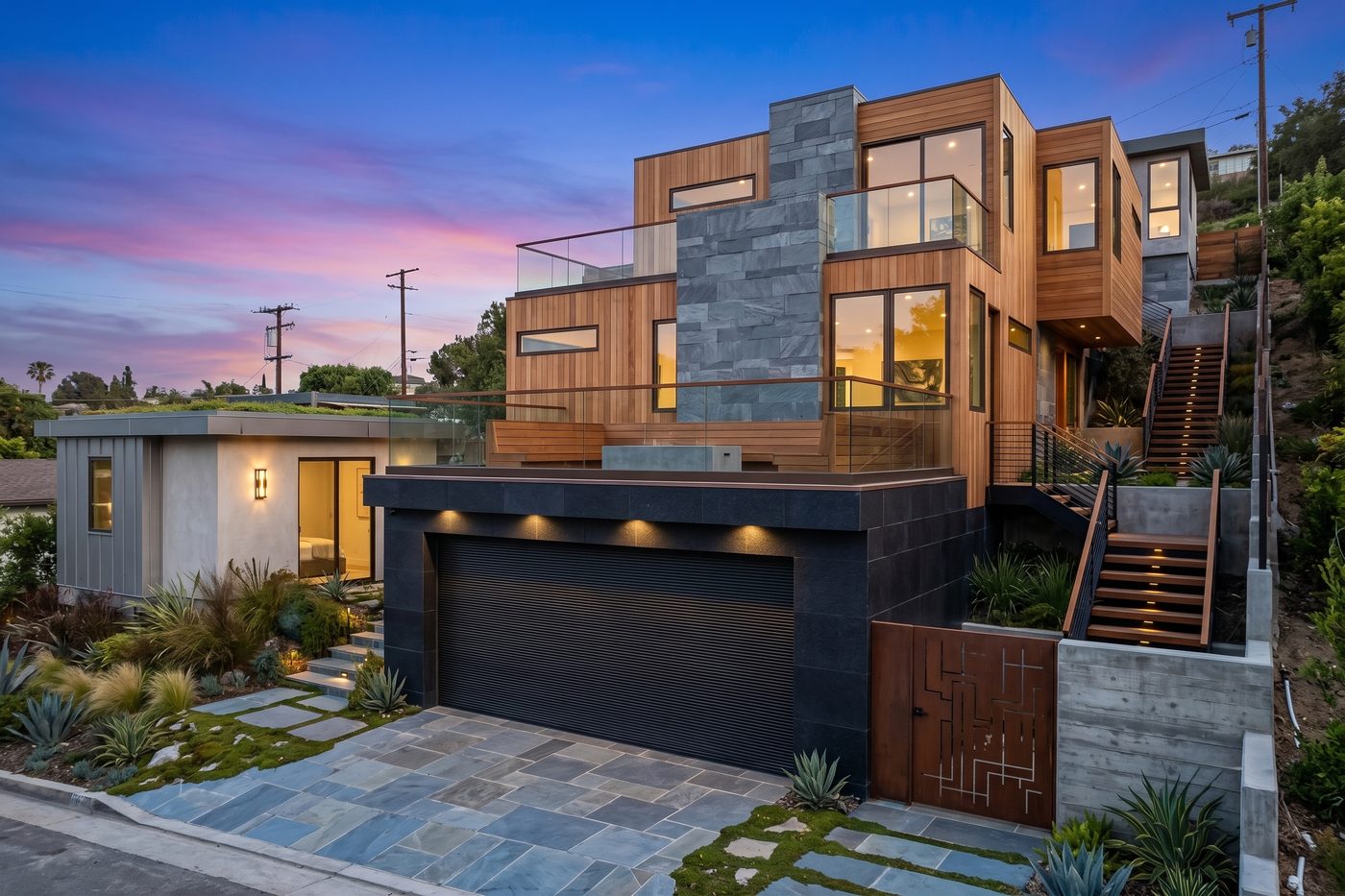 Hillside modern home with wood and slate exterior at dusk